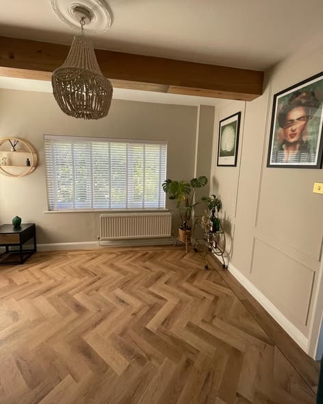 Herringbone oak parquet in a warm characterful living room with exposed period ceiling beam, plantation shutters and decorative bead chandelier