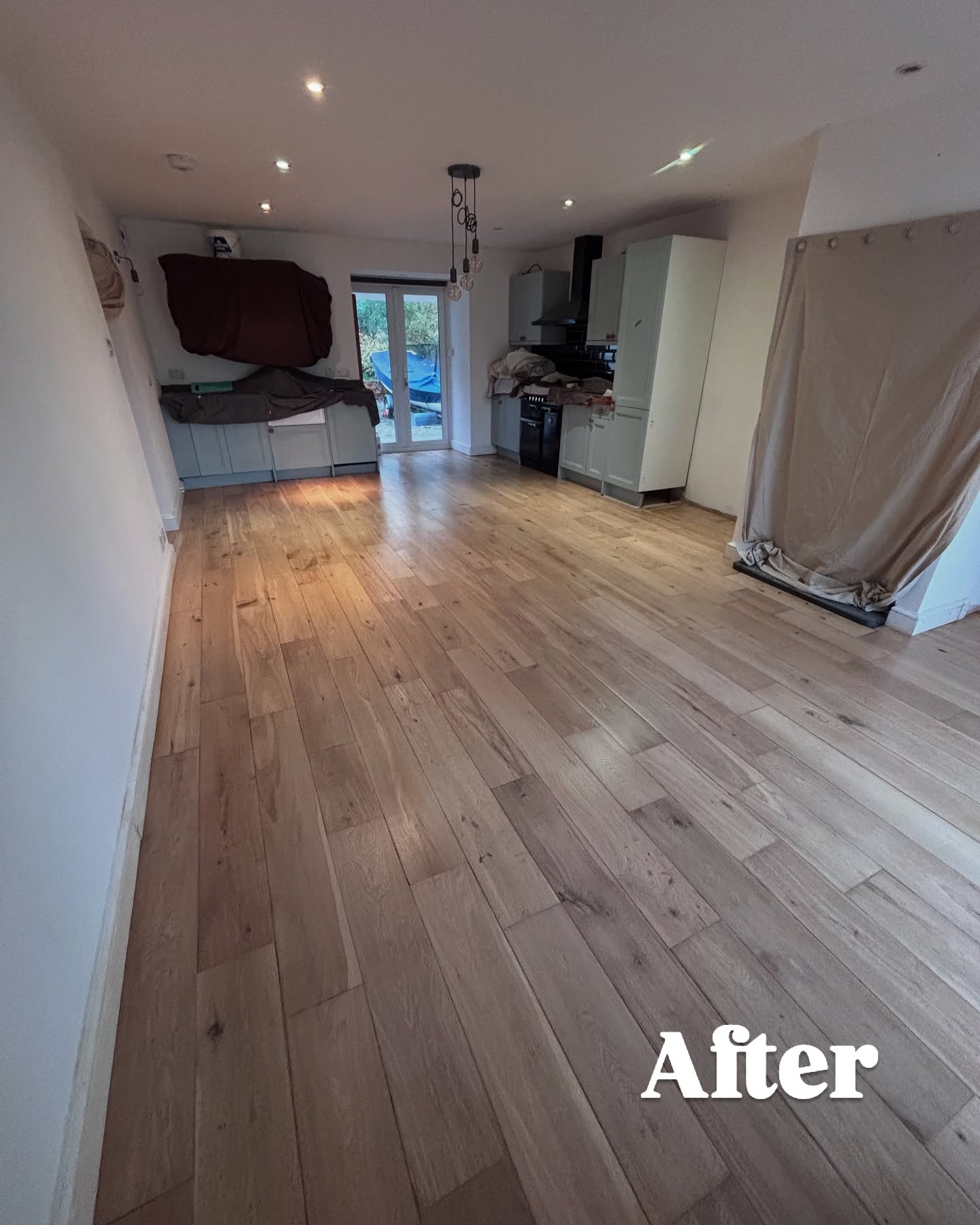Freshly installed wide-plank natural oak engineered flooring in a bright open-plan kitchen-diner after renovation