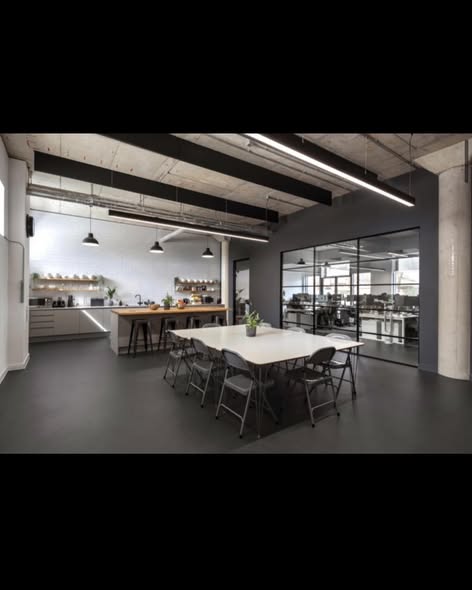 Dark grey resin flooring in a contemporary open-plan commercial office with exposed steel beams, meeting table and glass partition walls