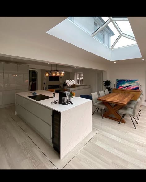 Light ash wide-plank flooring in a bright contemporary open-plan kitchen-diner beneath a large glass lantern roof extension